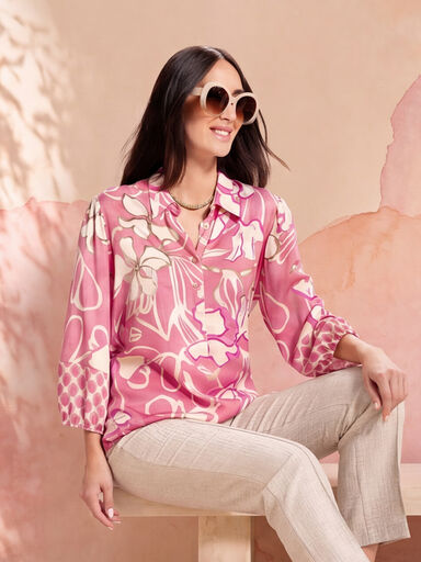 Sitzende Dame mit Sonnenbrille und rosa gebl&uuml;mter Longbluse