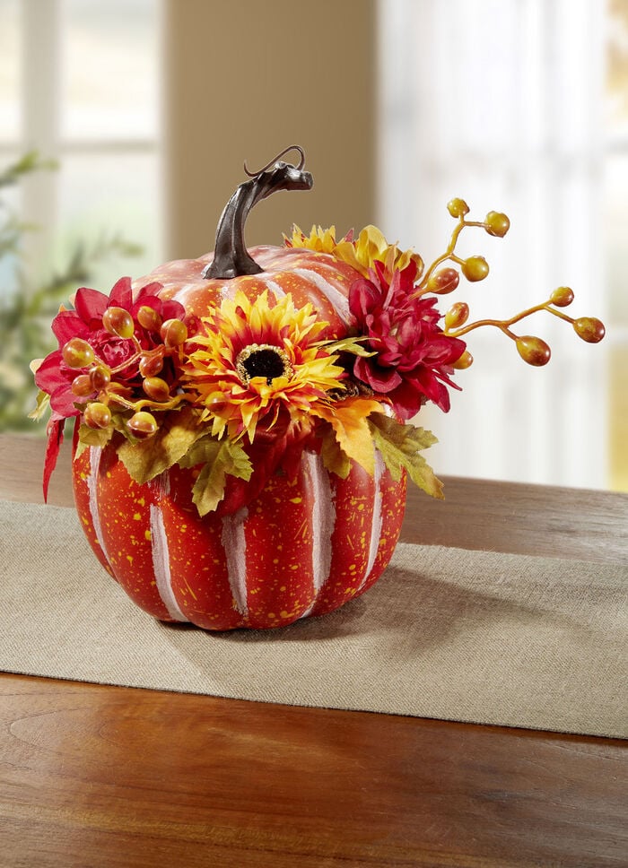 Deko-Kürbis mit kleinen Beeren und herbstlichen Blüten 