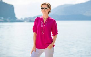 Dame mit pinker Bluse, weißer Hose und Sonnenbrille