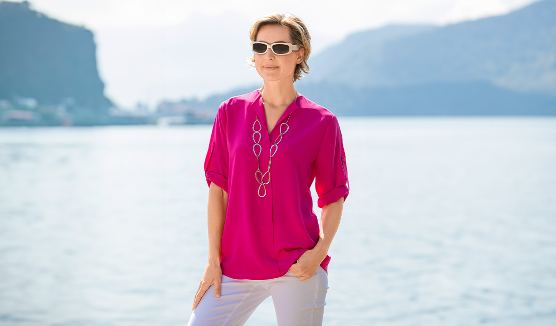 Dame mit pinker Bluse, weißer Hose und Sonnenbrille