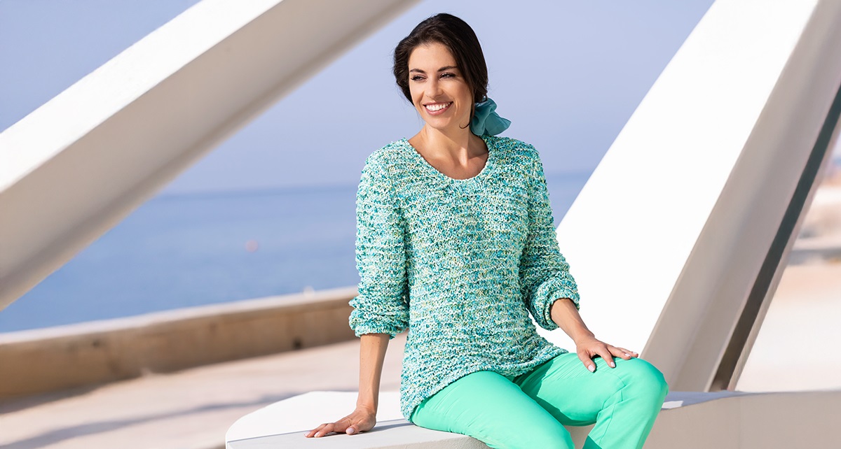 Frau in mintfarbenenm Pullover und Jeans